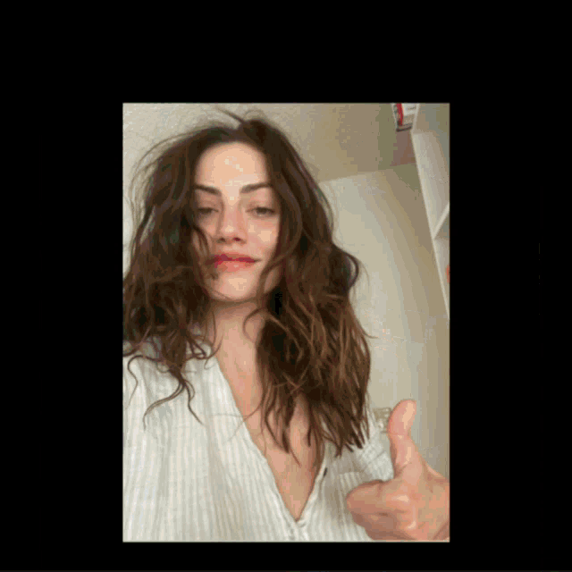 a woman giving a thumbs up in a white shirt