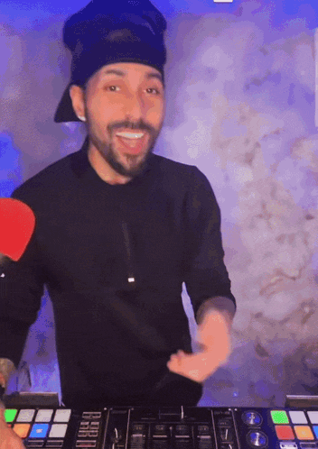 a man with a beard is standing in front of a pioneer dj controller
