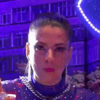 a close up of a woman 's face with a purple background and a purple light behind her .