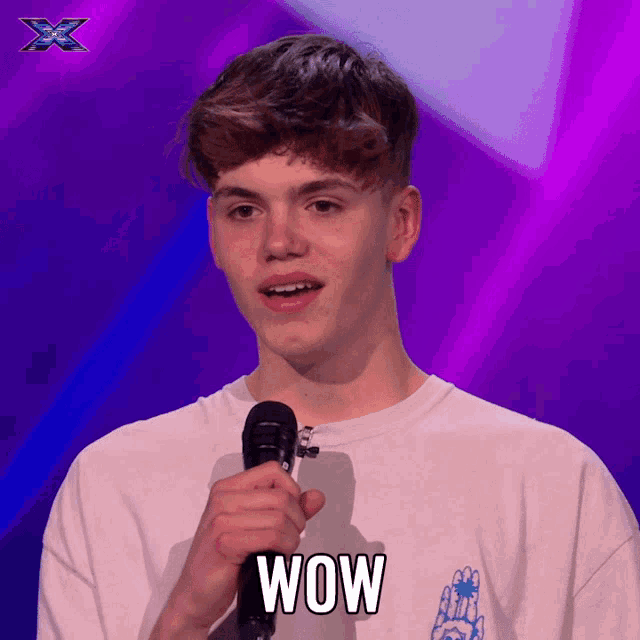 a young man holding a microphone with the word wow on his shirt
