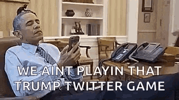 a man in a suit and tie is sitting in a chair looking at his cell phone .