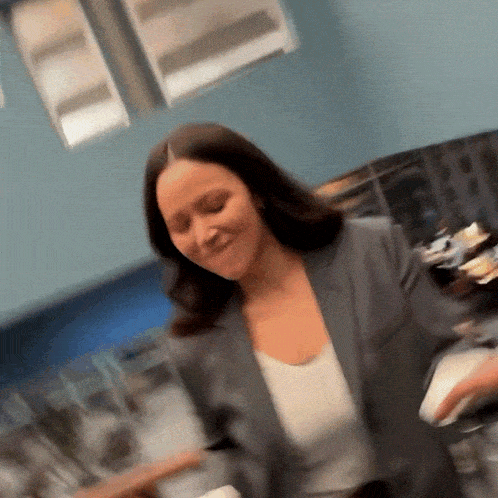 a woman in a suit and white tank top is dancing