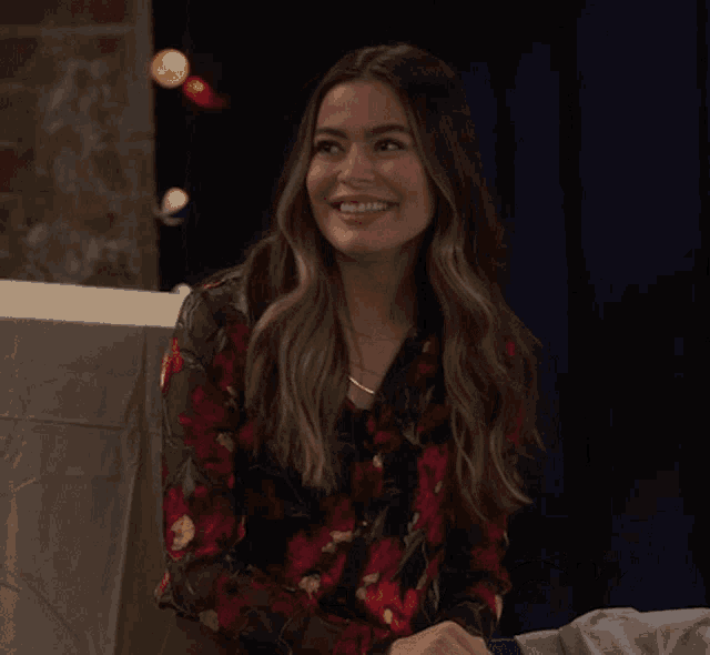 a woman in a floral shirt says " we 're back " while smiling
