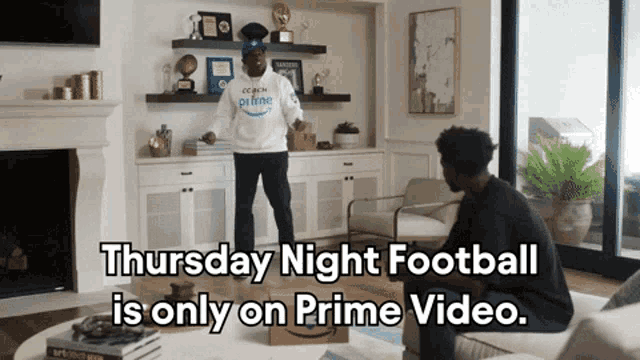 two men are sitting in a living room watching thursday night football