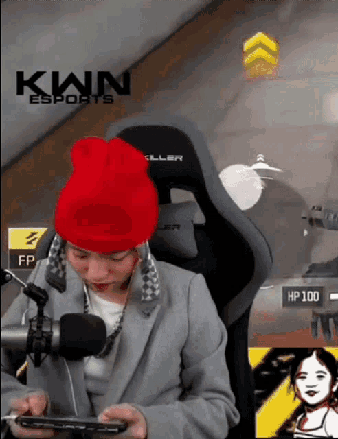 a person wearing a red beanie is playing a video game with the kwn esports logo in the background