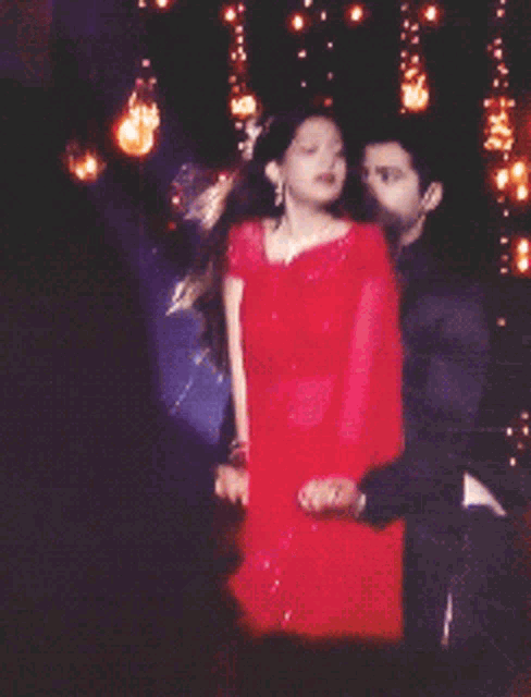 a woman in a red dress is holding a man 's hand
