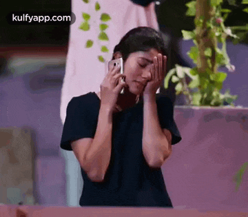 a woman is covering her face while talking on a cell phone