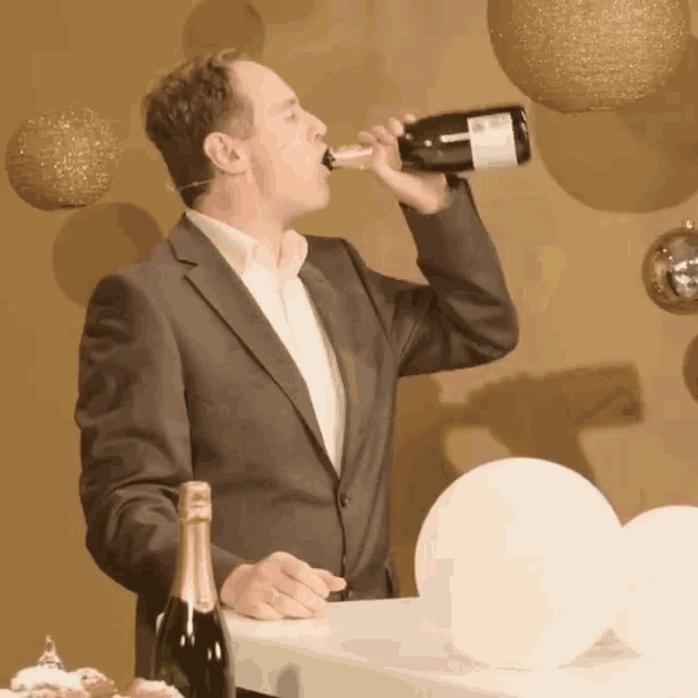 a man in a suit is drinking from a bottle