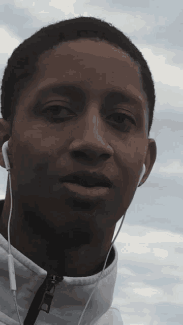 a young man wearing ear buds and a white jacket with the word asics on the front