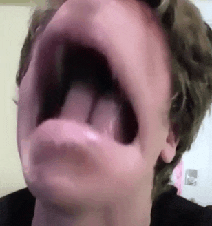 a close up of a person 's face with their mouth open and their tongue sticking out .