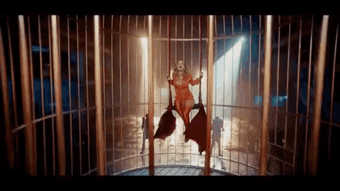 a woman in a red dress is hanging from a metal cage