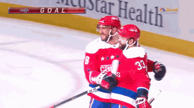 two hockey players celebrate a goal in front of a star health banner