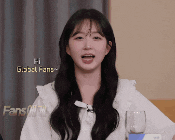 a girl says hi global fans while holding a glass of water
