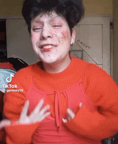 a woman in a red sweater is making a funny face while wearing makeup .