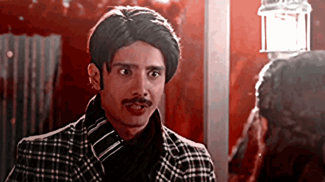 a man with a mustache wearing a plaid jacket and tie