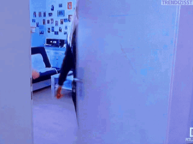a woman in a black jacket is standing in a doorway with the words trendizisst on the bottom