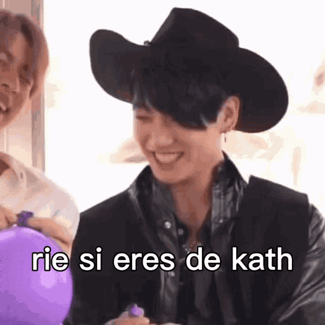 a man wearing a cowboy hat is holding a purple balloon and smiling .