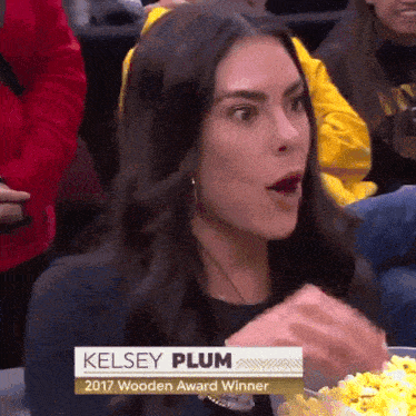 a woman named kelsey plum is sitting in a crowd eating popcorn