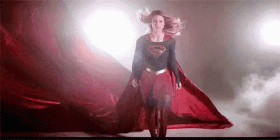 a woman in a superman costume is standing in a dark room .