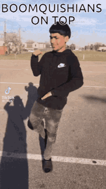a boy is dancing in a parking lot with the words boomquishians on top written on the bottom .
