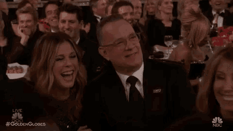 a man in a suit and tie is sitting in a crowd of people at a awards ceremony .