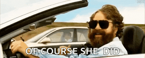 a man with a beard is driving a car with the words `` of course she did '' written on the screen .