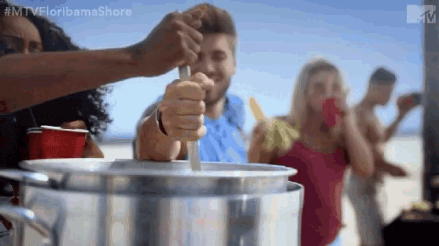a group of people are gathered on a beach and one of them is holding a spoon