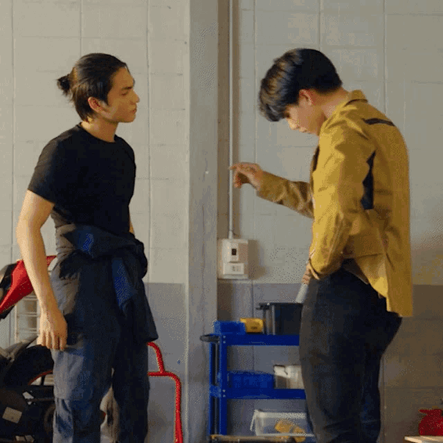 two men are standing next to each other in front of a wall