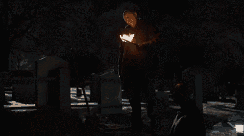 a man standing in a cemetery holding a torch