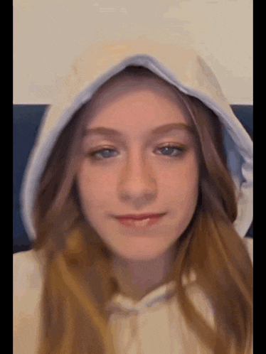 a young girl wearing a white hoodie with a hood on her head .