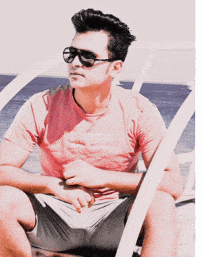 a man wearing sunglasses and a pink shirt sitting on a chair