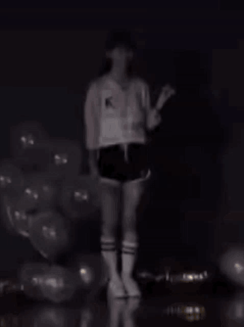 a woman is standing on a pile of balloons holding a stick .