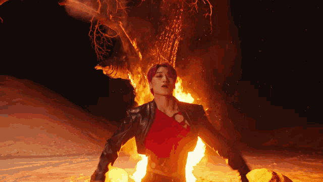 a man in a red shirt and black jacket is surrounded by flames