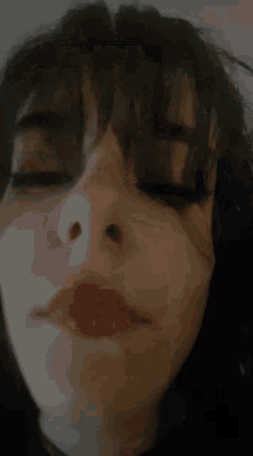 a close up of a woman 's face with red lipstick and a tear in her eye .