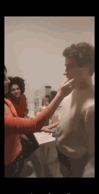 a woman touches a man 's face in a room with other people