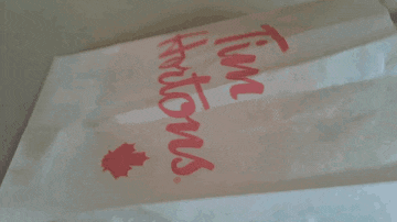 a person is holding a donut in a bag that says kfc