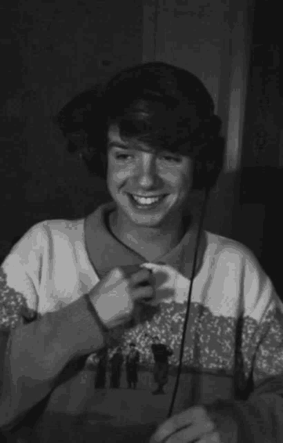 a black and white photo of a young man wearing headphones and a sweater .