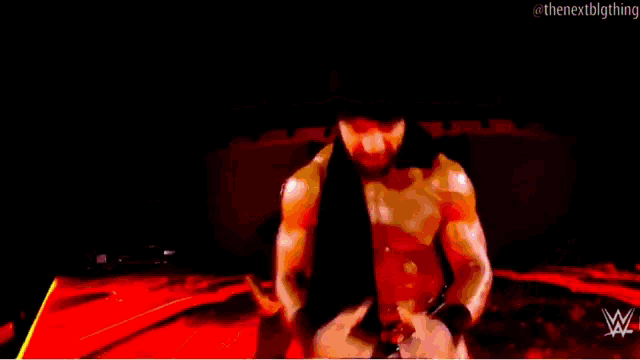 a man in a wrestling outfit is dancing on a stage while another man takes a picture of him .
