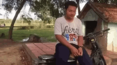 a man wearing an aeropostale shirt sits on a motorcycle .