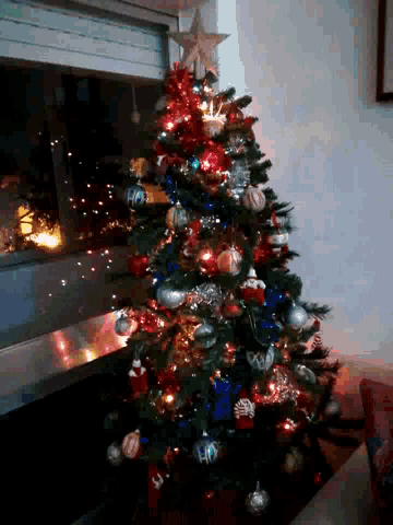 a christmas tree is decorated with red silver and blue balls