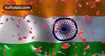 the flag of india is waving in the wind with petals falling from the sky .
