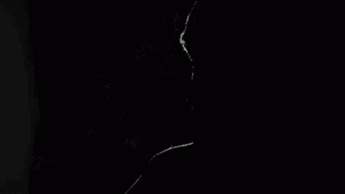 smoke is coming out of a person 's mouth on a black background in a black and white photo .