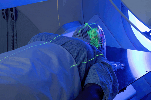 a person in a hospital gown is laying in a bed with a blue light shining on their head