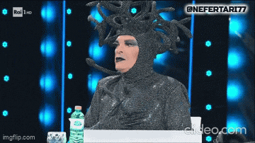 a man in a medusa costume is sitting at a table with a bottle of water in front of him