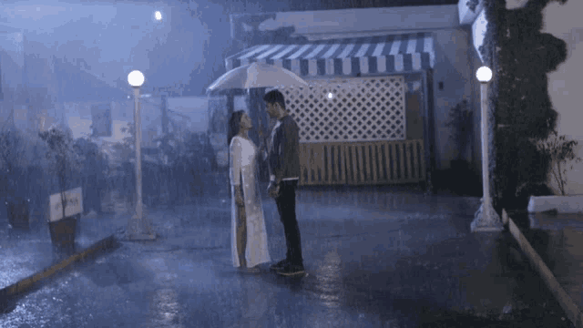 a man and a woman are kissing in the rain under an umbrella