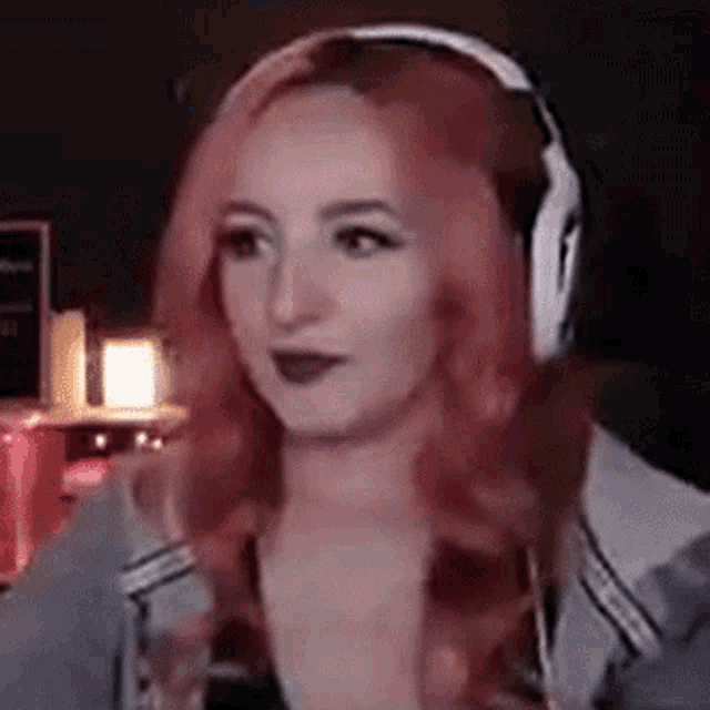 a woman with red hair is wearing headphones and making a face .