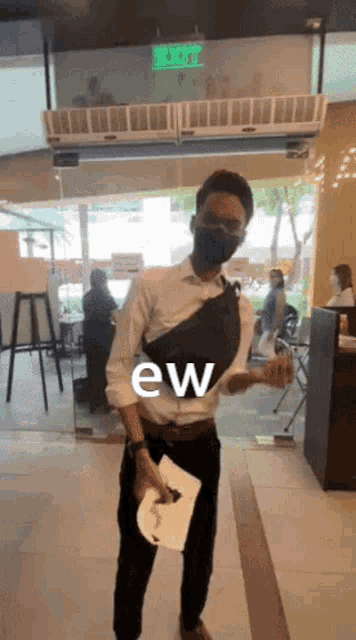 a man wearing a mask holds a piece of paper with the word ew on it