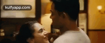 a man and a woman are kissing in a room and the man is touching the woman 's face .