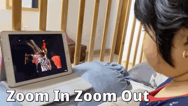 a woman is sitting in front of a tablet that says zoom in zoom out on the bottom