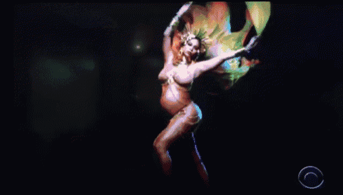 a pregnant woman is dancing on a stage in front of a cbs logo .